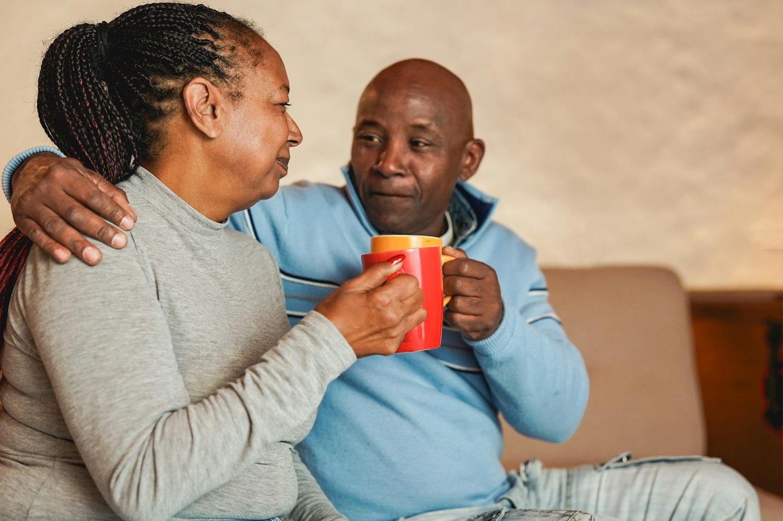 Happy african senior couple drinking together coffee at home