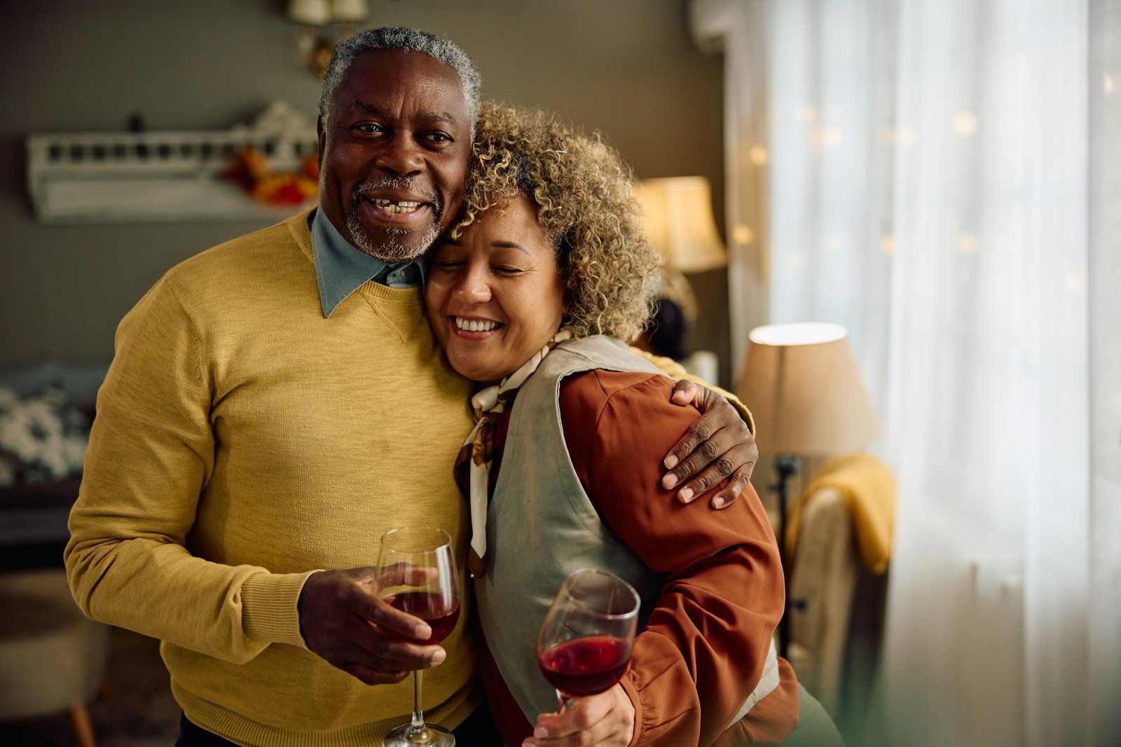 Happy senior couple embracing while having a glass of wine at home.